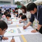 4월 19일 혁명국민문화제 시민 낙서장에서 어린이와 성인이 함께 분필로 도로에 그림을 그리고 글을 쓰고 있다