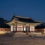 밤에 조명으로 환하게 빛나는 현충사 본전과 주변 건축물의 모습. 은은한 달빛 아래 고풍스러운 한국 전통 건축물이 더욱 아름답게 보인다.
