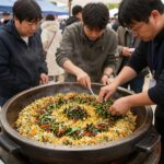 영양 산나물축제장에서 커다란 가마솥에 산나물 비빔밥을 만들고 있는 모습. 참가자들이 둘러서서 구경하고 있다.