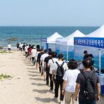 푸른 동해바다를 배경으로 대진항에 설치된 대문어축제 부스와 현수막, 그리고 방문객들이 줄지어 이동하는 활기찬 축제 현장 모습